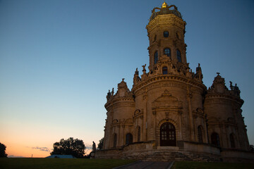 Obraz premium Beautiful entrance door with staircase to baroque medieval style old church building on nature bright evening light on sunset bright blue sky. Europe religion architecture building