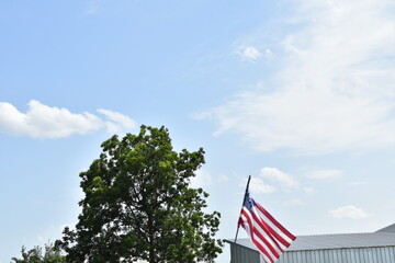 Fototapeta premium Sunny Sky Over American Flag in a Farm Field