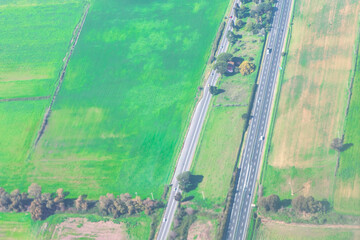 Aerial photo reveals multilane highway through patchwork of agricultural fields, with vehicles...