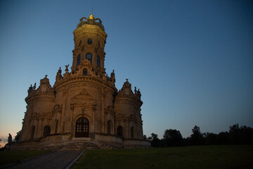 Fototapeta premium Beautiful entrance door with staircase to baroque medieval style old church building on nature bright evening light on sunset bright blue sky. Europe religion architecture building