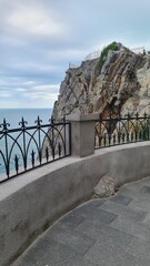 A scenic view of a rocky cliff overlooking the sea in Crimea. The sky is cloudy, and a decorative...