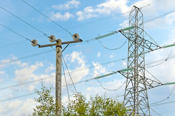 High Voltage Pylon and Power Lines in a Grassy Field Against a Blue Sky