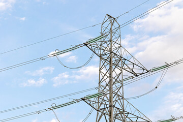 High Voltage Pylon and Power Lines in a Grassy Field Against a Blue Sky