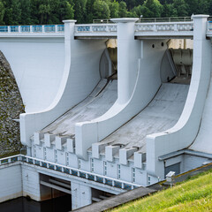 Massive concrete hydroelectric dam with curved spillways and gates. Modern infrastructure structure...