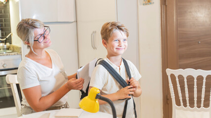 A mother helps her first-grade son pack his backpack for school