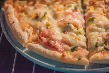 Ready-made pizza with bacon and cheese on a blue plate.