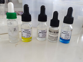 Close-up presenting five bottles with different colored solutions of Anti-A, Anti-B, and Anti-D...