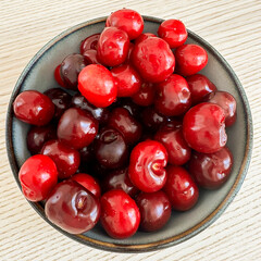 Freshly harvested cherries in a bowl on a wooden table during summer season