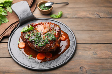 Traditional ossobuco dish with beef steak and sauce served on wooden table, closeup. Space for text