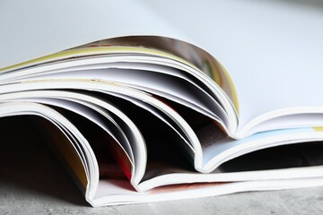 Different open magazines on grey table, closeup