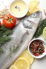 Fresh raw seabass with spices on white table, flat lay. Fish and seafood delicacies