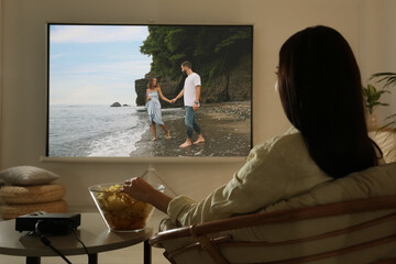 Young woman watching movie using video projector at home