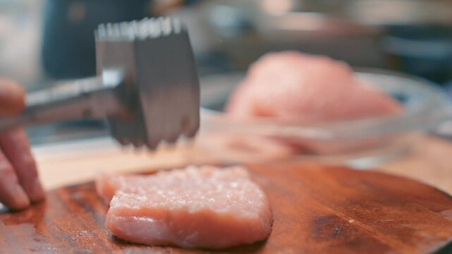 Turkey fillet being tenderized with meat mallet on wooden board slow motion