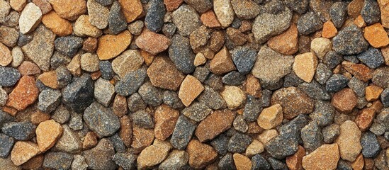 Naklejka premium Close-up view of assorted small pebbles and stones in various shades of brown, orange, grey, and black creating a natural textured pattern