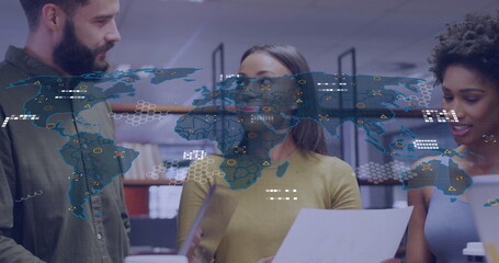 Three professionals wearing colorful tops discussing documents in office, with digital map overlay