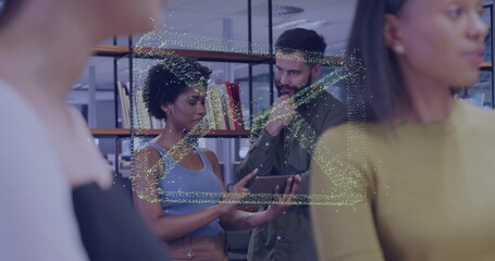 Pointing woman wearing blue top showing tablet to white man in office library, with bookshelves