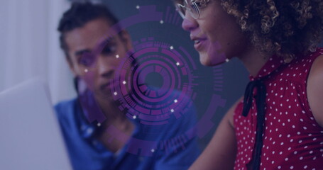 Collaborating tech team analyzing purple digital graphic at office desk with laptop and eyeglasses