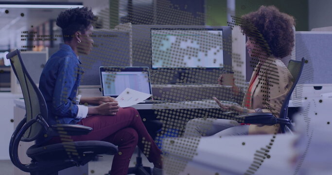 Reviewing printed reports, colleagues in office wear holding coffee cup at open-plan office desks