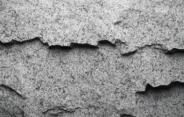 Obraz premium Close-up texture of peeling and cracked gray paint on a rough concrete or wall surface showing irregular layers and weathered decay
