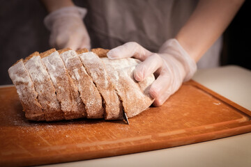Baker Slicing Freshly Baked Bread on a Wooden Cutting Board