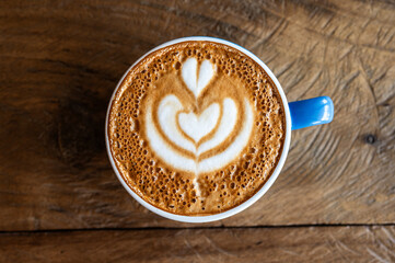 A hot cup of Cappuccino coffee serving on wooden table. The taste of cappuccinos can be described as creamy, smooth, and balanced.