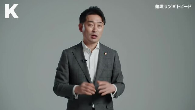 Asian Man In Gray Suit Explaining on Gray Background In Corporate Presentation With Formal Atire Looks Confident With Expertise and Knowledge