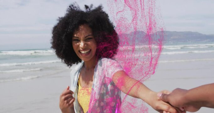 Woman stepping holding partner hand and initiating AR pink particle swirl in beach tech demo
