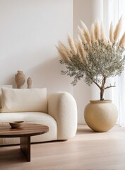 A minimalist living room features a cream-colored sofa, a round wooden coffee table, and a large pampas grass arrangement in a beige pot.  Natural light streams from a window