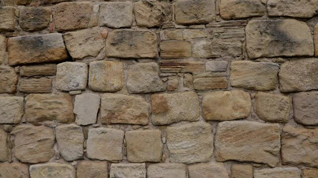 Close up view of an old weathered sandstone wall showing various textures and patterns, suitable for backgrounds and design projects