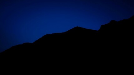 Fototapeta premium Mountain range silhouetted against inky sky
