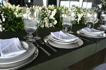 table set in ballroom, elegant wedding reception table with candlesticks, luxury dinner arrangement with floral centerpiece, formal dining table with clear chairs and silver candelabras