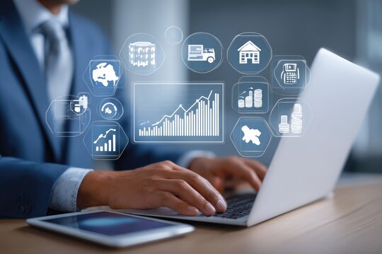 Businessman using laptop with financial and logistics icons overlayed