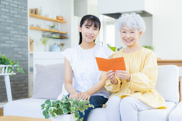 リビングで年金手帳を見る祖母と孫