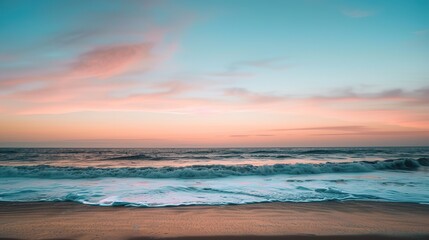 Fototapeta premium Soft pastel sunset painting the sky over a calm ocean beach, with gentle waves lapping the shore. The sky blends hues of pink, blue, and purple, while the water mirrors the serene colors, 