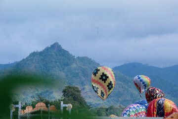 Traditional hot air balloons rise against a scenic mountain backdrop during a cultural festival in...