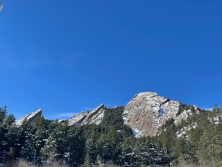 Panoramic view of snowy Flatiron Mountains of Boulder, Colorado with blue sky