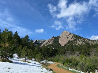 Panoramic view of snowy Flatiron Mountains of Boulder, Colorado with hiking path