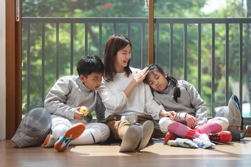 The fencers' families rest on the floor as they wait for the next round of the competition. Mother,...