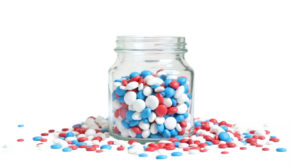 A glass jar filled with red, white, and blue candies spilled on a surface