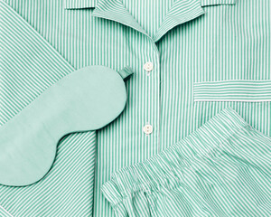 Pajama with silk sleep mask pastel mint colored on white sheet. Top view fashion woman home...