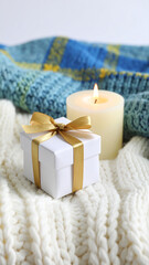 Serene Gift and Candle: A single lit candle, with a gift-wrapped box, nested amidst a cozy, comforting setting of soft, textured materials, and muted tones.