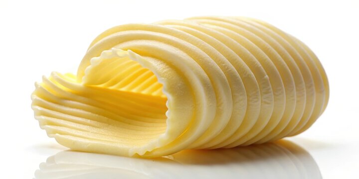 A pat of fresh butter with a curl shape melting on a plain white background