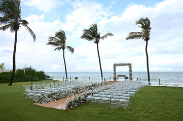 outdoor wedding ceremony altar overlooking the sea, surrounded by palm trees and with a central...
