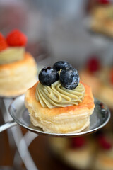 mini vol-au-vents,  mini puff pastry tarts topped with cream and berries, elegant dessert pastries served on tiered stand, assorted fruit vol-au-vents for high-end event buffet

