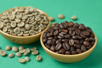 Fototapeta premium A Bowl of Roasted Coffee Beans and Bowl of Green Unroasted Coffee Beans on a Green Background