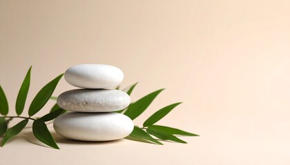 Stacked White Stones with Green Leaves on Beige Background Evoking Tranquility and Balance
