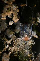 candle in the glass, hanging glass lanterns with lit candles at night event, romantic candlelight decor for outdoor celebration, elegant suspended candle holders glowing in the dark
