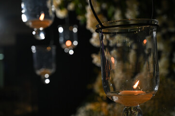 candle in the glass, hanging glass lanterns with lit candles at night event, romantic candlelight decor for outdoor celebration, elegant suspended candle holders glowing in the dark

