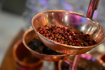 red hot pepper, pink peppercorns in copper spice bowl at buffet, gourmet pepper mix served in elegant setting, close-up of colorful peppercorns in rustic dish

