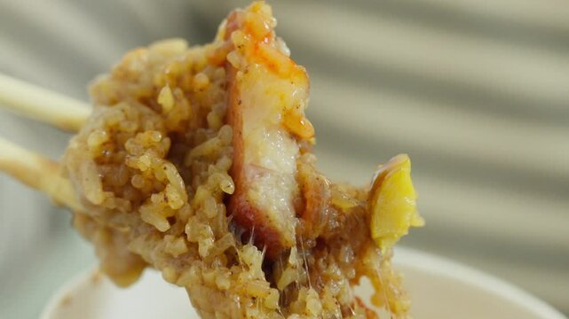 A Fujian-style rice dumpling is held close to camera&mdash;revealing sticky glutinous rice and savory meat filling, capturing tactile warmth, festive flavor.